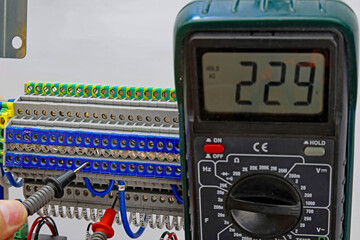 Measurement of electrical parameters in a switchboard using a multimeter.