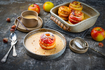 Traditional oven baked apples with crushed nuts, cinnamon and butter served with home made vanilla sauce as close-up in a design plate