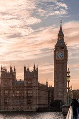 Scenic view of Big Ben and the Palace of Westminster along the Thames River, beautifully illuminated by a warm sunset sky.