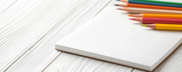 Colorful pencils rest on a clean sketchbook, encouraging creativity and inspiring artistic expression on a wooden desk