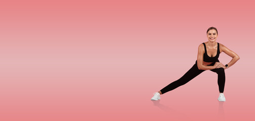 A woman in athletic wear performs a side lunge, showcasing flexibility and strength. The vibrant pink background adds energy to this workout setting.