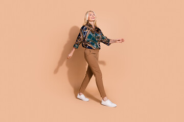 Obraz premium Photo of blonde hair strolling pensioner business lady in glamour formal outfit going looking empty space isolated on beige color background