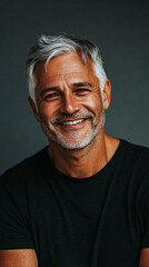 Obraz premium Portrait of a confident and joyful mature man with grey hair and beard, wearing a black t-shirt against a neutral background in a studio setting