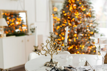 A decorated table with exquisite candles, plates and glasses. New Year or Christmas style