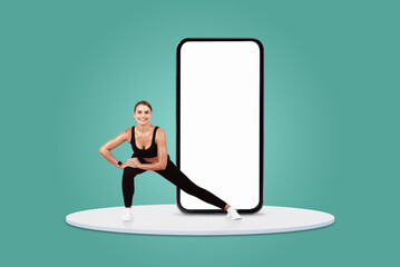 A woman in athletic wear performs a stretching exercise next to a large blank smartphone on a round...