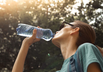 Young woman drinking water on sunny day 