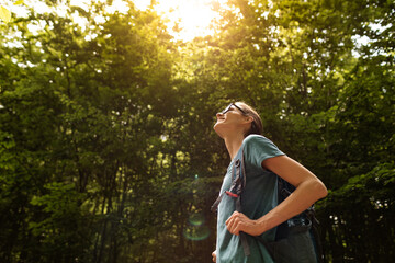 Young woman hiking walking through the forest enjoying the warm sunshine 