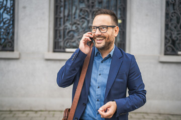 Adult businessman walk around city and talk on mobile phone