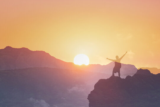 Will power, and overcoming life difficulties, never give up, silhouette of man on top a mountain 