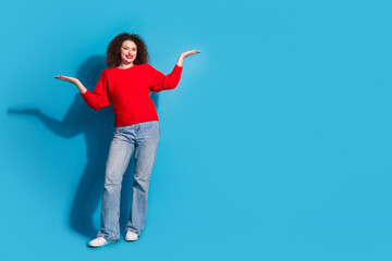 Full length photo of lovely young lady hold compare empty space dressed stylish red garment isolated on blue color background