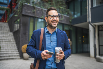 Adult businessman walk around city with thermos and use mobile phone