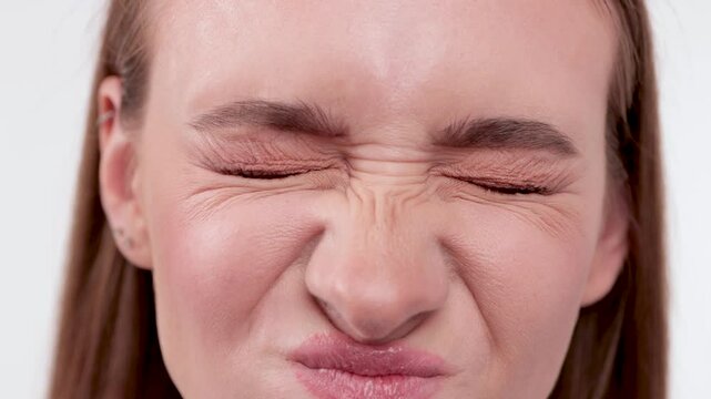 Close-up of a young woman's blue eyes. Her face shows expression lines around her eyes and between her eyebrows.