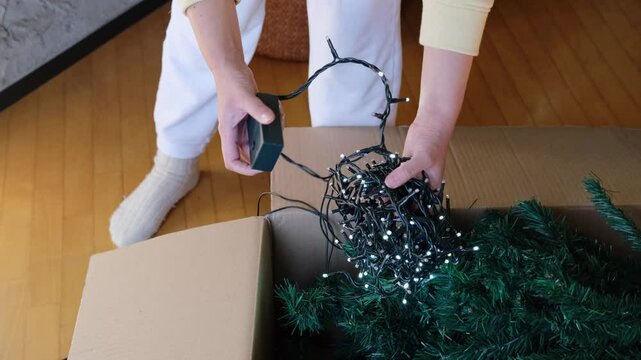 close-up of a woman's hands turning on and off a garland for a New Year's Christmas tree, preparing for the holiday, Getting ready for Christmas and New Year celebration