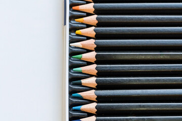 A close-up of a row pencils in a tin container.
