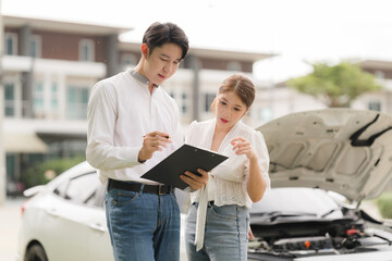 Car Trouble: A concerned couple reviews insurance paperwork, facing a potential vehicle breakdown....