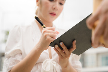 Focused Woman Taking Notes: Close-up shot of a woman meticulously taking notes on a clipboard,...