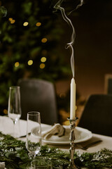 Vertical shot of extinguished wax candle in silver candlestick on decorated tale for Christmas party