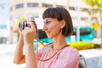 A young traveler takes photographs of the city using an analog camera. female photographer with a...