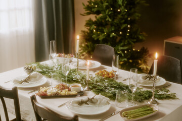 High angle shot of decorated table with appetizers, fur tree with golden lights in dining room
