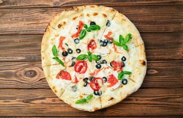 Pizza with mozzarella cheese , olives , chicken , pineapple , basil and tomatoes