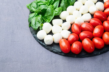 Basil leaves , cherry tomatoes and mozzarella cheese . In form italian flag food photography