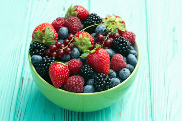 Mix of ripe colorful berries in bowl photography . Blueberry , strawberry , raspberry , blackberry and red currant . Top view