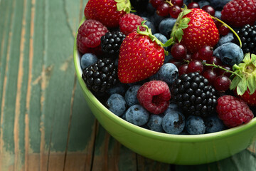 Mix of ripe colorful berries in bowl photography . Blueberry , strawberry , raspberry , blackberry and red currant . Top view