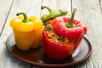 Baked stuffed pepper ( paprika ) with rice , carrot and meat . Top view on rustic background