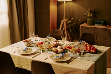 High angle shot of table with different types of desserts, pastry and snack on polished plates in dining room