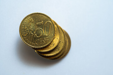 A close-up of a 50 euro cent coin on a white background. The bright gold color and shallow depth of field make the details of the coin, such as the embossed numbers and the map, stand out. Perfect for