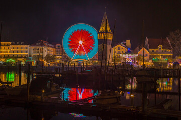 Nachtaufnahme von einem Jahrmarkt mit Riesenrad und Kettenkarusell am Bodensee.