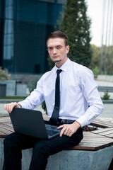 Caucasian man with laptop, manager on city center background. Freelancer