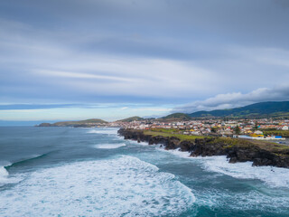 Ribeira Grande on the Atlantic ocean coast in Sao Miguel island, Azores, Portugal. Aerial drone view of city, cliffs and wavy ocean