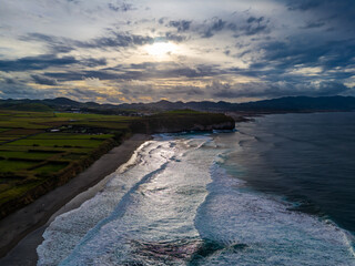 Santa Barbara beach with volcanic sand and turquoise Atlantic ocean waves in Sao Miguel, Azores. Aerial drone view of coast in Ribeira Grande town