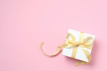 Beautiful gift box tied with bow on color background 