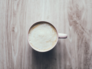 A cup of coffee sits on a wooden table