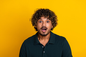 Fototapeta premium Surprised young man in black shirt against yellow background expressing shock and excitement