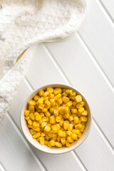 Canned sweet corn in bowl on white table.