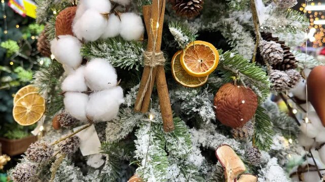 Close up of a christmas tree being decorated with a gingerbread man, dried orange slices, cinnamon sticks, pine cones and cotton flowers
