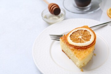 Slice of tasty semolina cake served on white table, closeup. Space for text