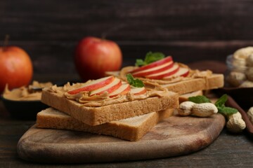 Tasty sandwiches with peanut butter, apples, nuts and mint on wooden table, closeup