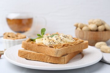Tasty sandwich with peanut butter, banana, chia seeds and mint on table, closeup