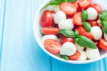 Basil leaves , cherry tomatoes and mozzarella cheese . In bowl food photography