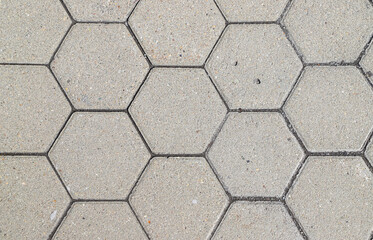 Texture of a sidewalk paved with hexagonal gray tiles as a background