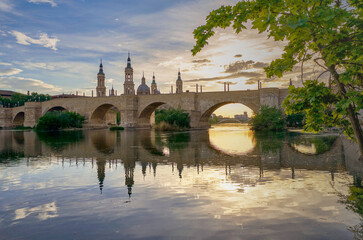 View on the Stone Bridge and Basilica of Our Lady of the Pillar on the banks of Ebro river at sunset. Zaragoza, Spain