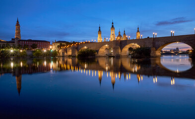 View on the Stone Bridge and Basilica of Our Lady of the Pillar on the banks of Ebro river  in blue hour. Zaragoza, Spain