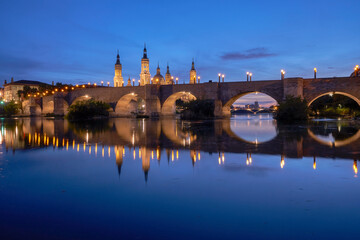 View on the Stone Bridge and Basilica of Our Lady of the Pillar on the banks of Ebro river  in blue hour. Zaragoza, Spain