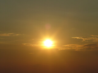 Sky with yellow sun rays during sunset and small clouds - natural golden sunny background. Topics: weather, sun energy, season, beauty of nature, dusk, evening, air space