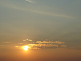 Sky with yellow sun during sunset and small clouds - natural golden sunny background. Topics: weather, sun energy, season, beauty of nature, dusk, evening, air space