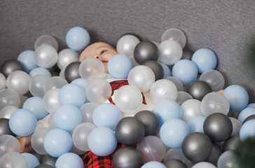 A playful moment of a baby surrounded by colorful balls in a cozy play area